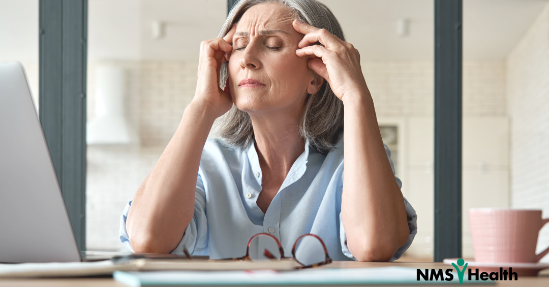 Woman rubbing her temples in an office